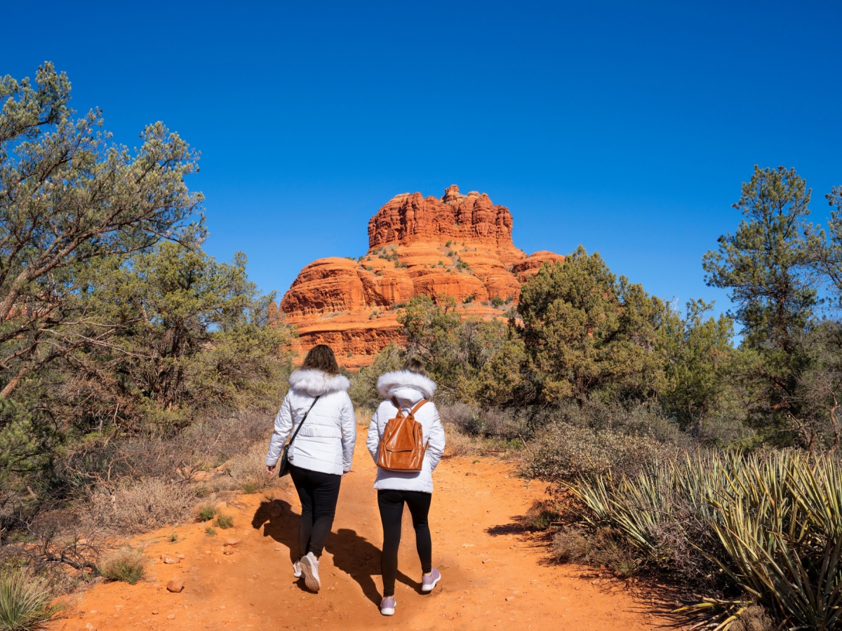 Two Women in winter coats and leggings hiking through Sedona.